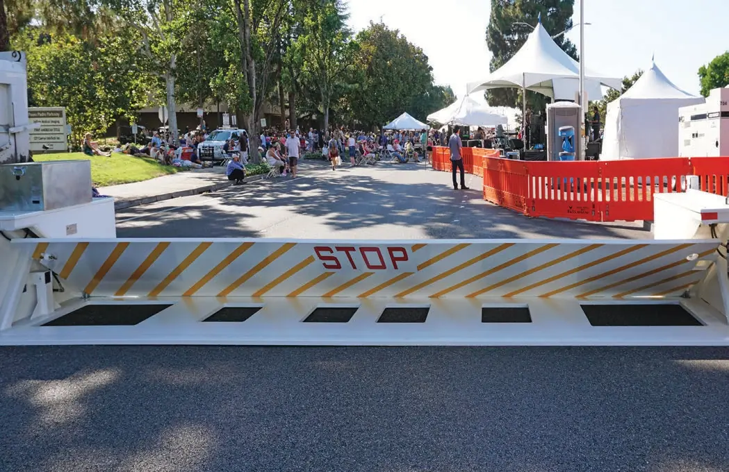 Temporary white barrier with diagonal yellow stripes and red "STOP" text at an event.