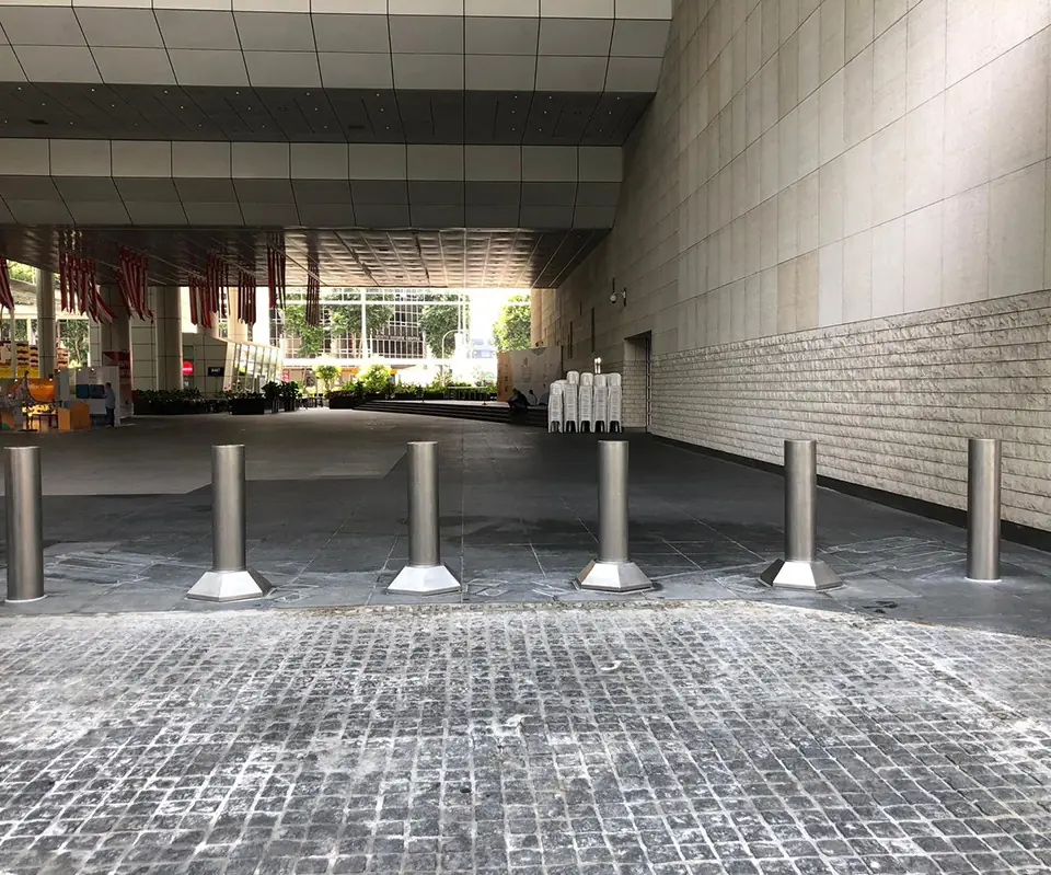 Silver Matador bollards line the entryway of a modern building with high ceilings and walls.