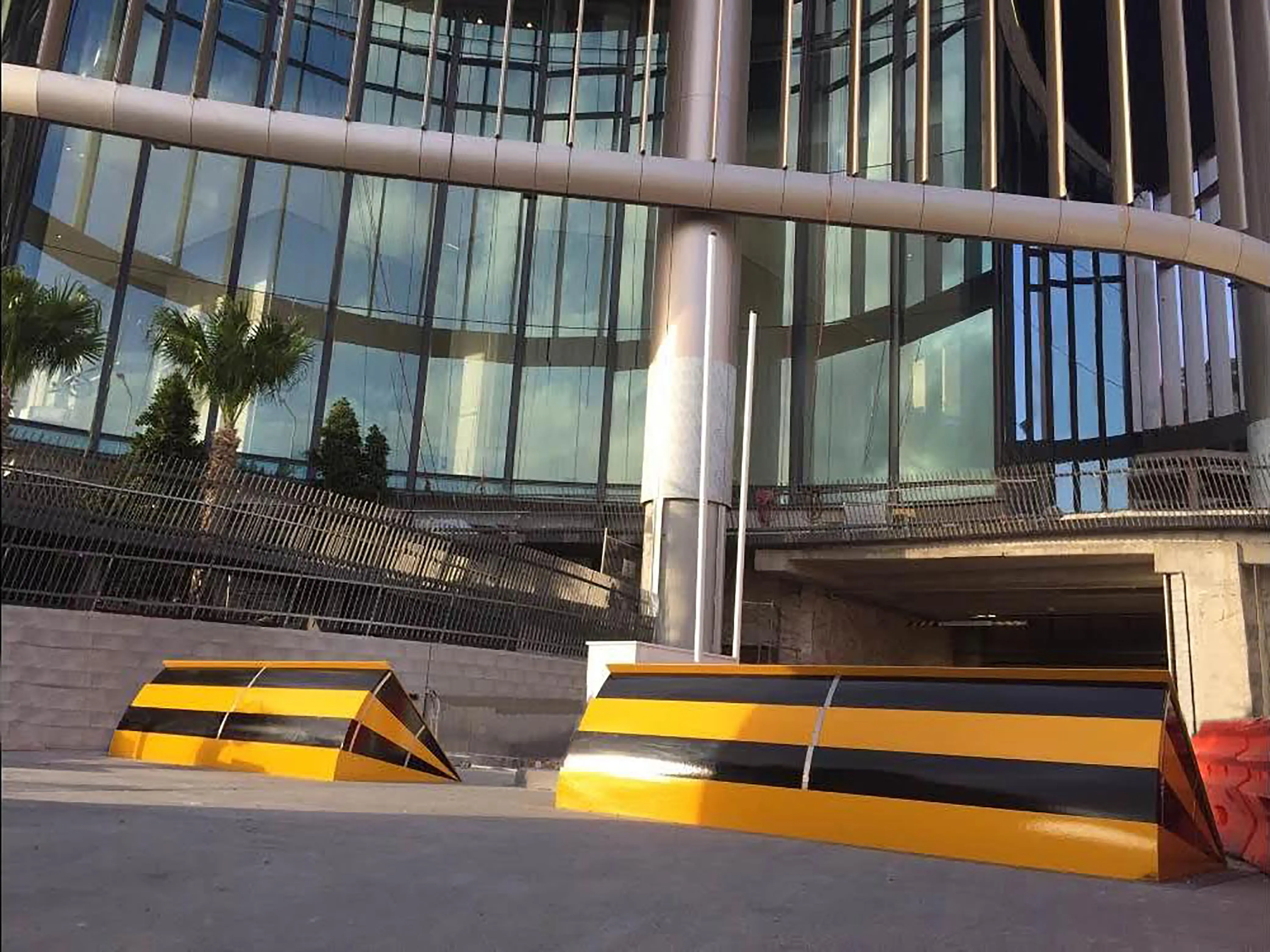 A pair of yellow-black Viper wedge barriers installed on a sloped driveway near a commercial building entrance.