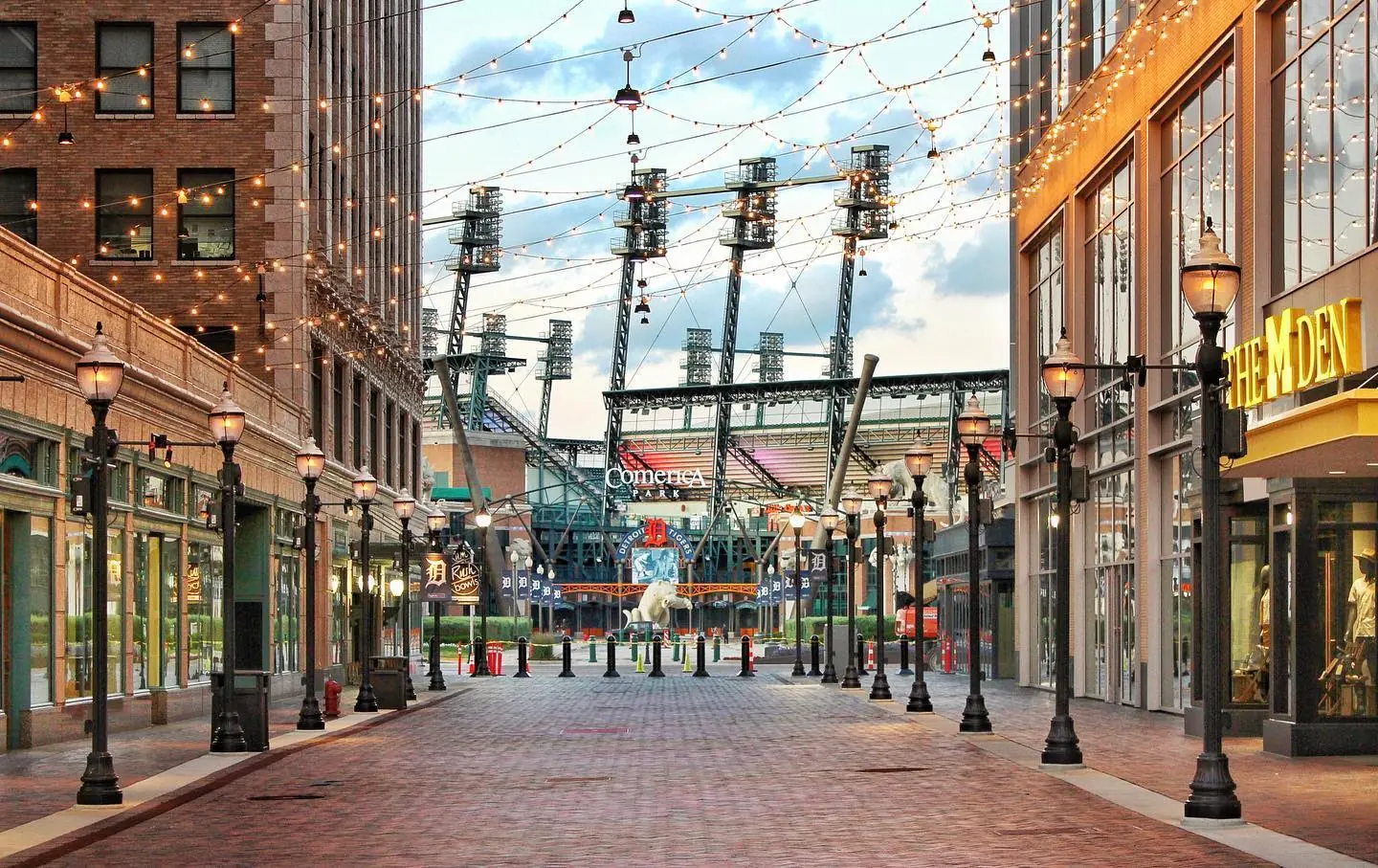 String lights and bollards lining a brick-paved pedestrian street near Comerica Park.