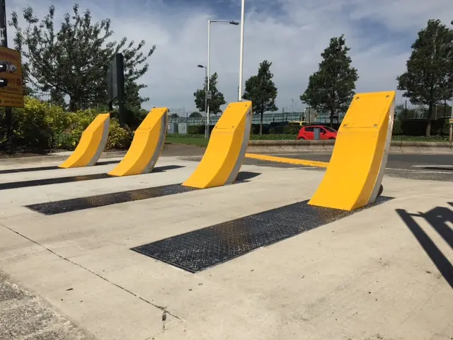 Shallow mount bollards with a yellow finish are positioned across a paved vehicle entrance.